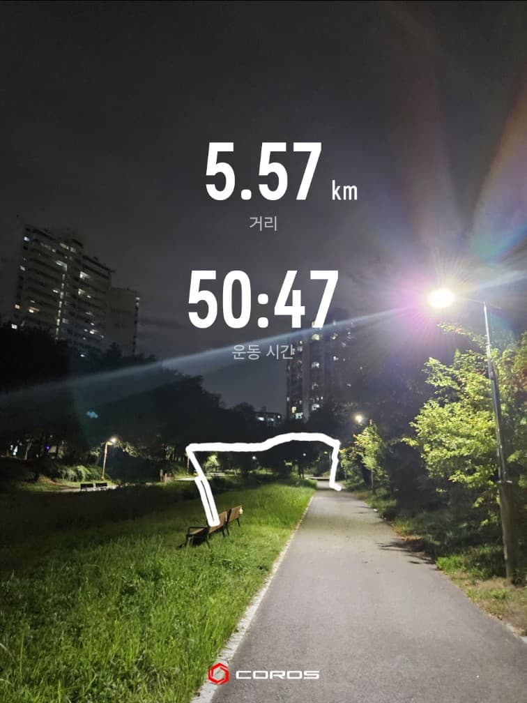 A COROS workout photo showing 5.57 km and 50 minutes 47 seconds over a neighbourhood path lit by streetlights at night