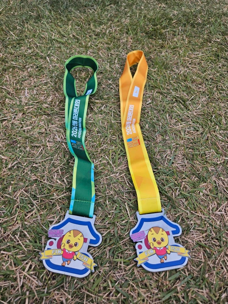 Two 2026 Andong Marathon finisher medals placed on grass